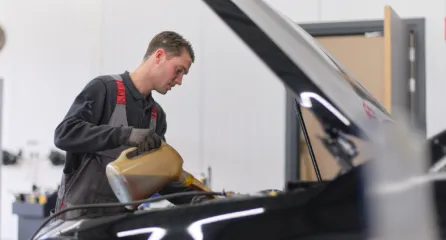 Profielfoto bij de functie allround medewerker in de sector mobiliteit. Man vult de motorolie bij van een auto.