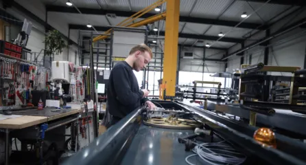 Profielfoto van technicus. Man voert montagewerk uit aan een grote metalen constructie in een werkplaats.