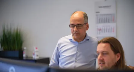 Profielfoto van twee mannen. Kijken samen naar een computerscherm op kantoor.