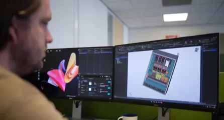 Profielfoto van de functie engineer. Man kijkt naar een technisch 3D-model op dubbele computerschermen op kantoor.