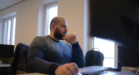 Profielfoto van man werkt achter een computer op een kantoor.