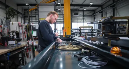 Profielfoto bij de functie monteur, werkt geconcentreerd aan de bedrading van een technische installatie in een werkplaats.