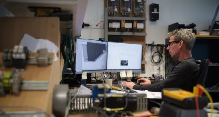 Profielfoto van de functie ontwerper. Engineer werkt aan een 3D-ontwerp op een computerscherm in een technische werkruimte.