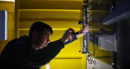 Profielfoto van aankomend monteur elektra in de sector energie die werkt aan een elektrisch paneel.