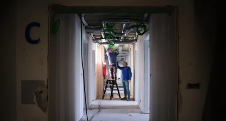 Profielfoto bij de functie Technicus / leidinggevende monteur in de sector installatietechniek. Monteur werkt aan een plafond binnen een nieuwbouwproject en wordt begeleid door de leidinggevende monteur.