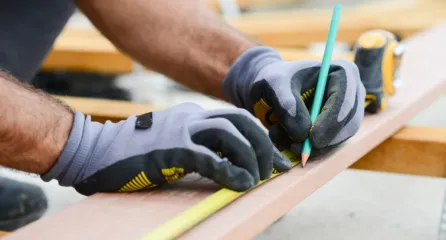 Profielfoto bij functie timmerman. Handen meten en markefen houten balk met potlood.