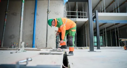 Profielfoto van de functie van betontimmerman. Betontimmerman met boormachine boort in een betonnenvloer