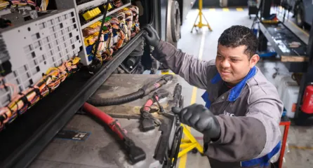 Profielfoto functie monteur mobiele werktuigen sector infra. Monteur werkt aan een vrachtwagen in een werkplaats.