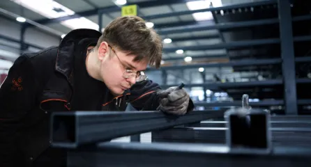 Metaalbewerker controleert nauwkeurig een stalen constructie in de werkplaats.