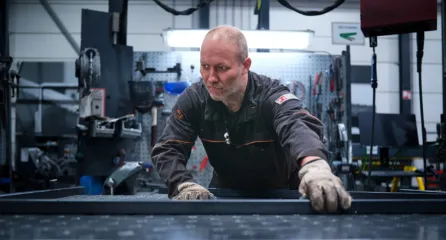 Profielfoto bij de functie assemblagemedewerkers in de sector metaal richt een stalen frame uit op de werkbank in een fabriekshal.