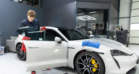 Profielfoto bij de functie autopoetser in de sector mobiliteit. Een man poetst een witte sportauto in een moderne werkplaats.