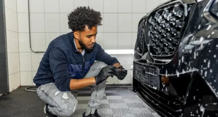 Profielfoto bij de functie autodetaillist in de sector mobiliteit. Man is met de afwerking van een kentekenplaat bezig.