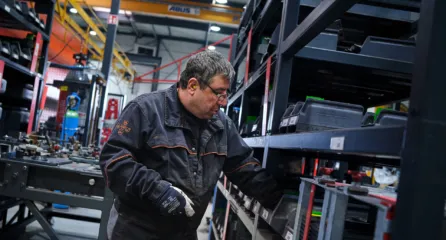 Profielfoto bij de functie gereedschapsmaker. Monteur zoekt onderdelen in een magazijnrek op de werkvloer van een fabriekshal.